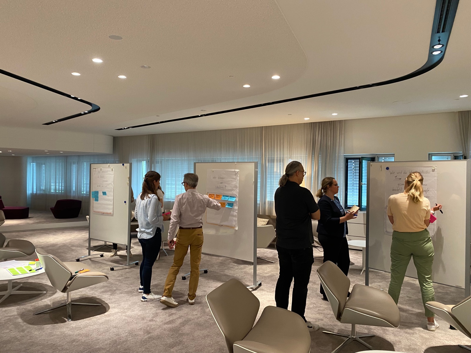 Teilnehmende arbeiten beim Mastermind in München gemeinsam an Workshop-Tafeln
